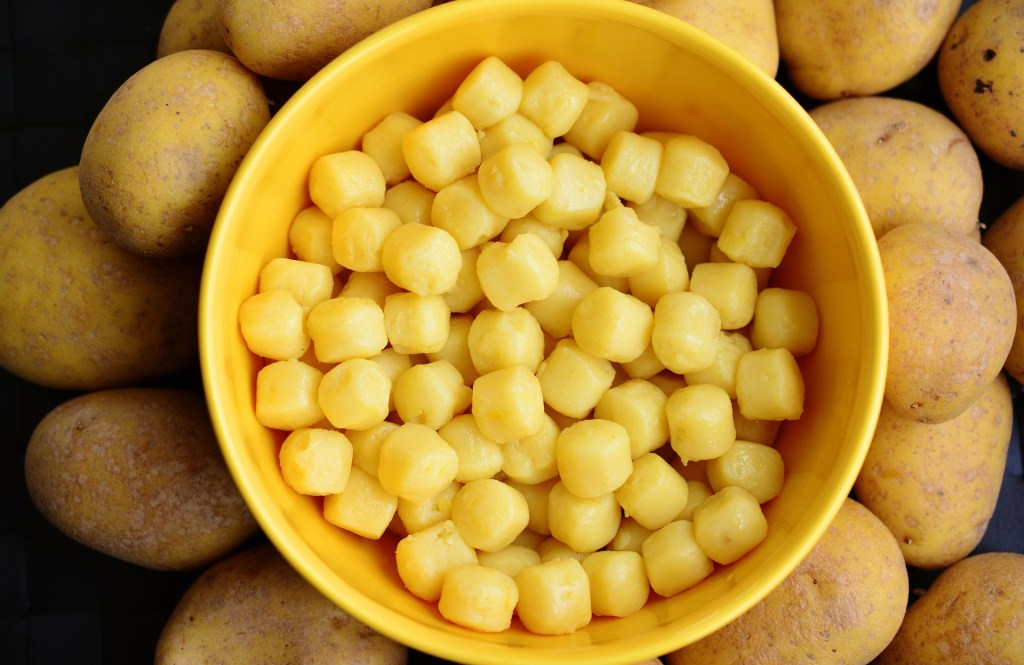 Image of a bowl of gnocchi surrounded by potatoes